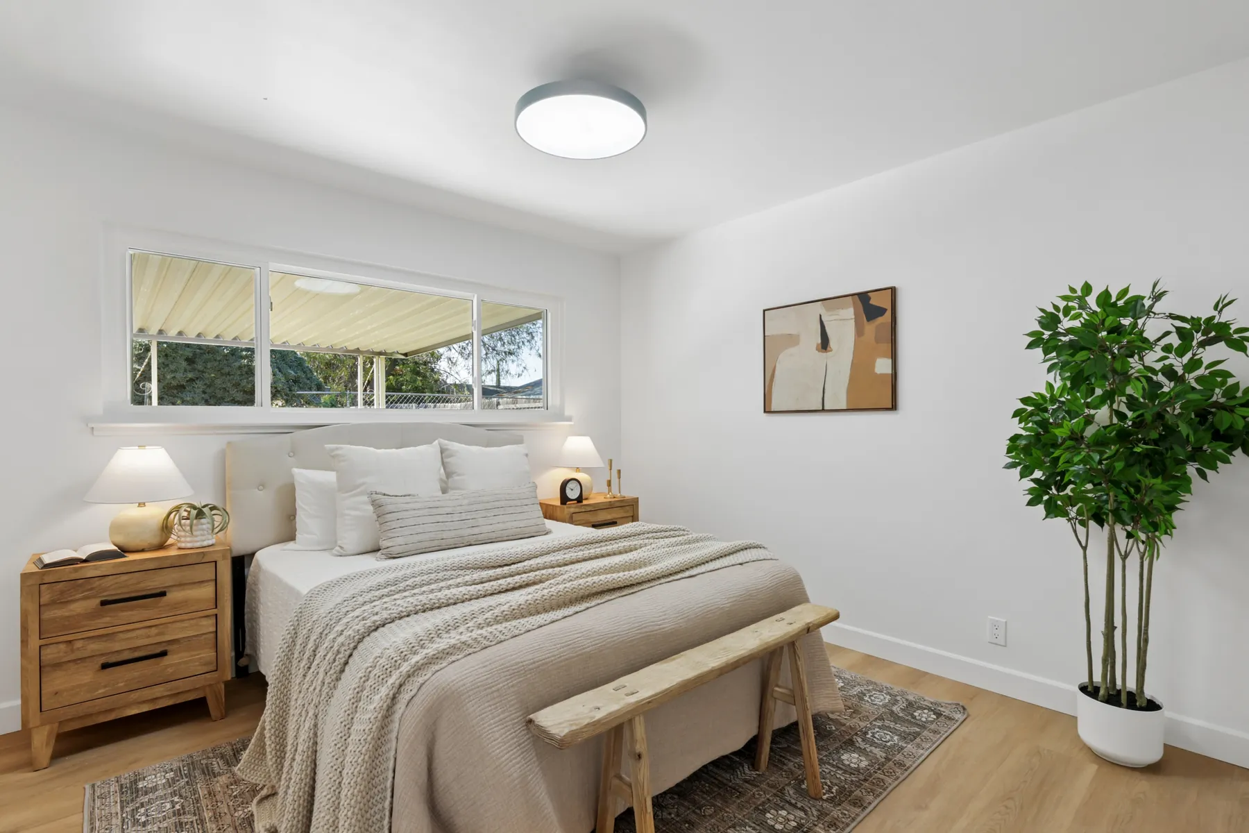Bedroom with wood-look plank flooring and a ceiling-mounted light fixture. Furniture shown is staging.